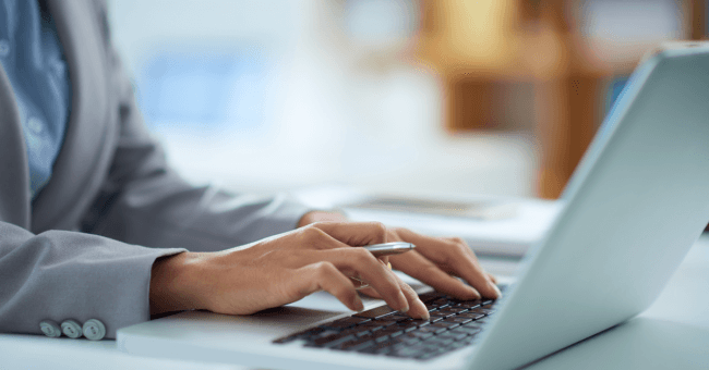 Person typing on a laptop while reviewing a legal document translation